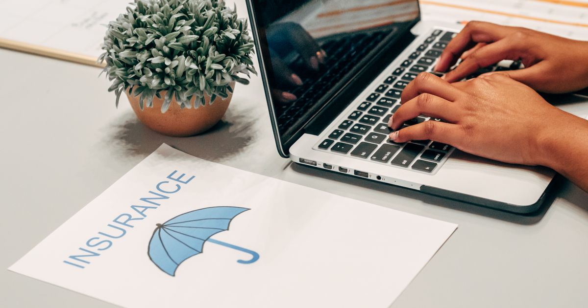 Hands typing on a laptop beside an insurance document — checking mental health benefits in Maryland